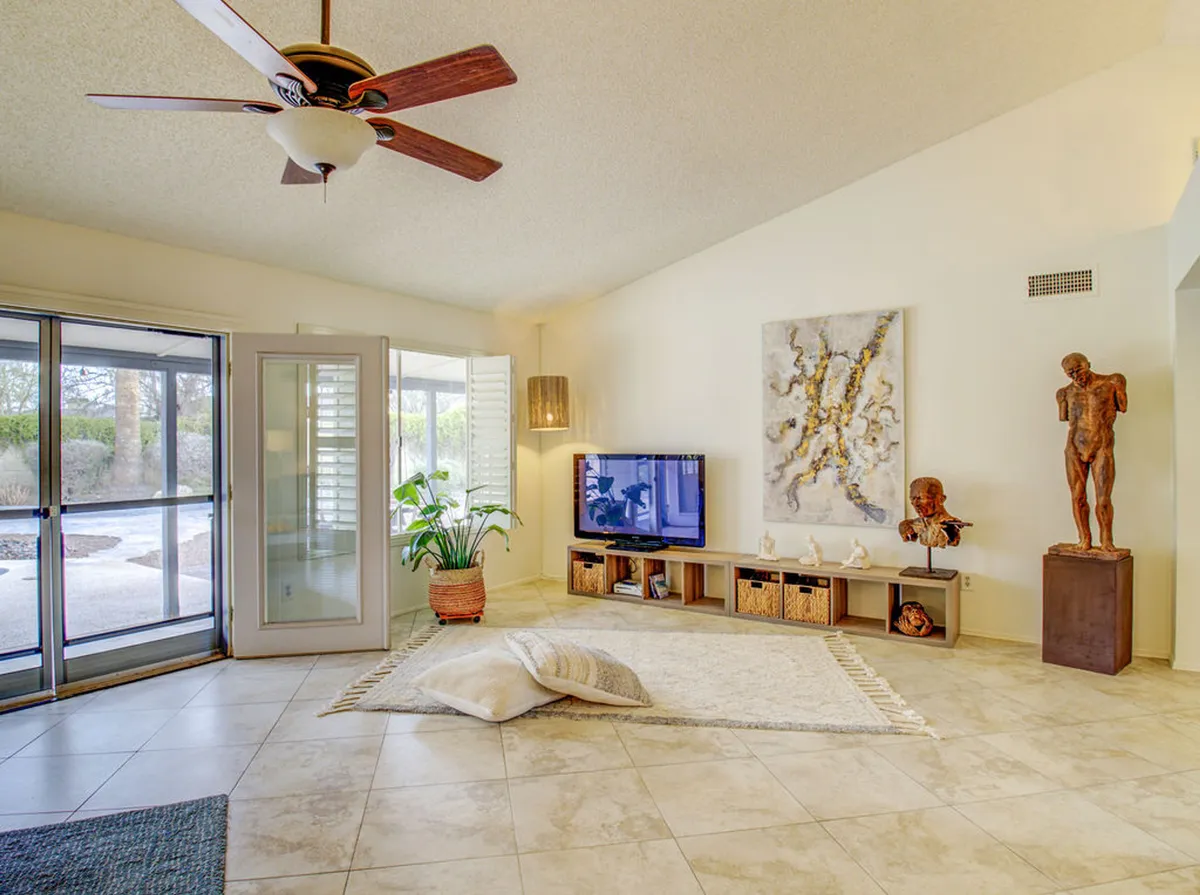 This image captures a view from the home’s living area, with large glass doors opening to the outdoor space, inviting natural sunlight inside. The scene hints at easy indoor-outdoor flow, with morning sunlight spilling into the room and a glimpse of the inviting patio just beyond the doors.