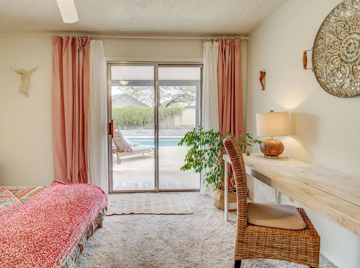 This image reveals a tranquil bedroom with a sliding glass door that leads out to the pool area. The view through the door features sunlight, suggesting a bright, inviting spot where families can step straight into the heart of outdoor fun.